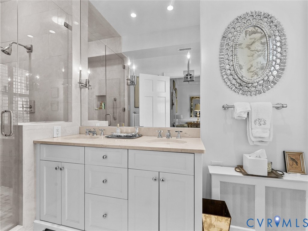 Double vanity featuring white cabinetry, stone countertops, dual integrated sinks,