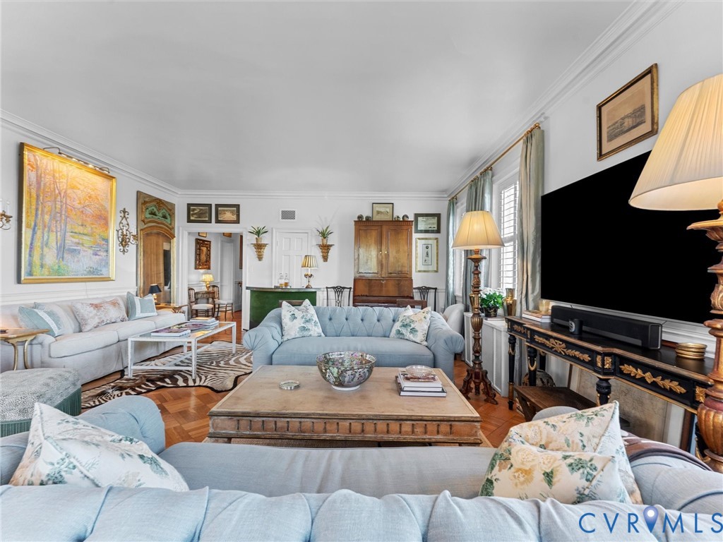 Living area featuring intricate parquet wood flooring, crown molding, and wainscoting