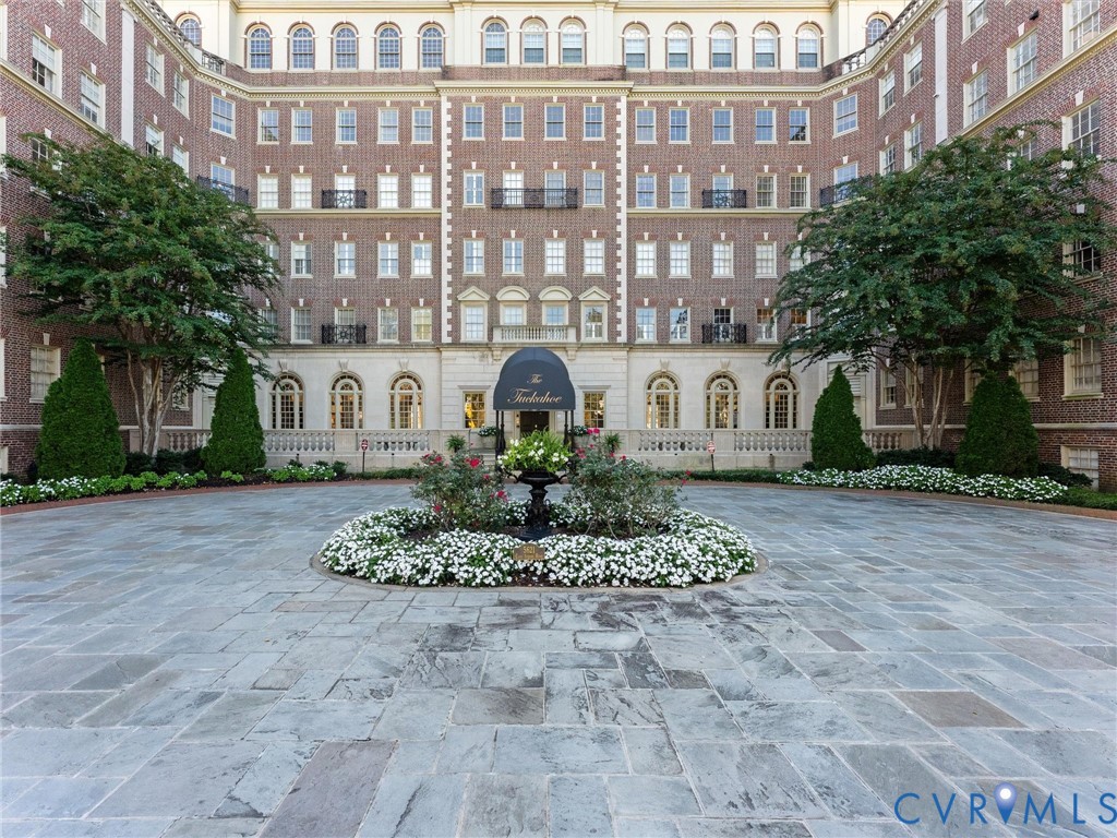 Brick exterior facade featuring a symmetrical architectural design, arched window detailing, stone balustrade, central portico entrance, and a paved stone motor court Brick exterior facade featuring a symmetrical architectural design, arched window detailing, stone balustrade, central portico entrance, and a paved stone motor court