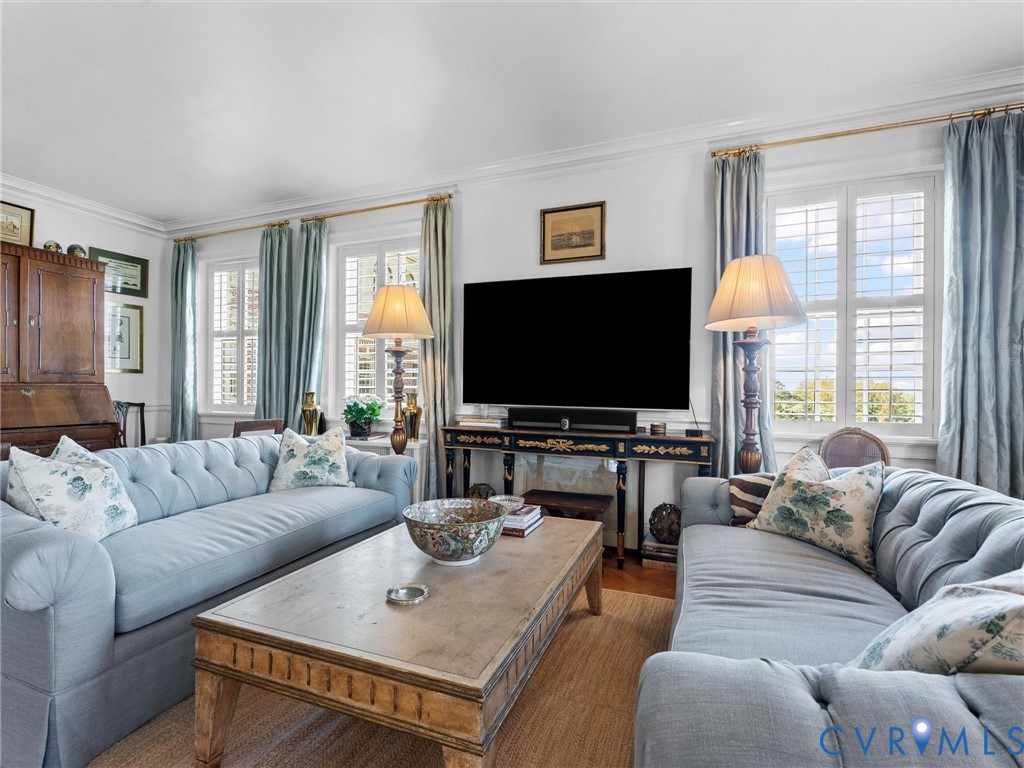 Living area featuring crown molding, neutral wall finishes, and plantation shutters