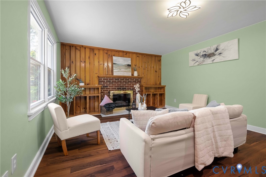 Wood-finish flooring, brick fireplace with metal insert, built-in wooden shelving, and decorative ceiling light fixture Wood-finish flooring, brick fireplace with metal insert, built-in wooden shelving, and decorative ceiling light fixture