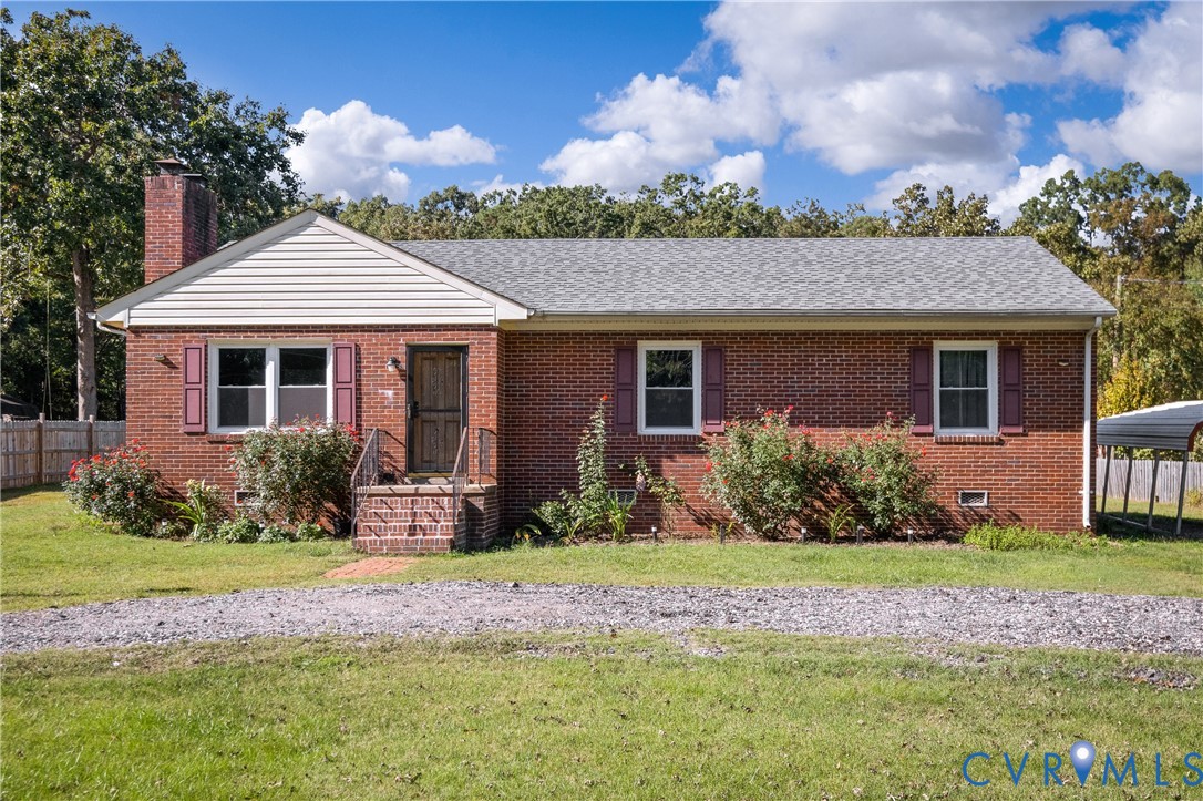 Red brick exterior featuring a masonry chimney, gabled roofline, decorative window shutters, and a covered brick-step entryway