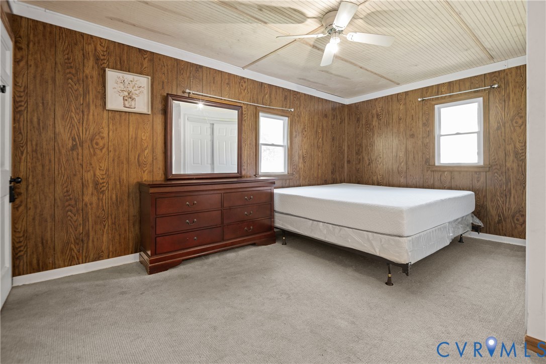 Wood-panelled walls, tongue-and-groove ceiling, and ceiling fan with integrated lighting