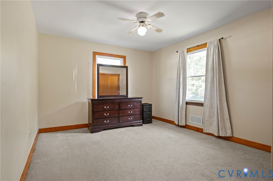 Neutral-toned carpeting, wood-trimmed window, and central ceiling fan with integrated lighting