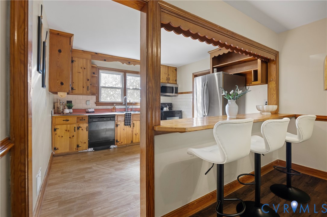 Kitchen featuring natural wood cabinetry, subway tile backsplash, built-in breakfast bar with wood countertop, and stainless steel appliances