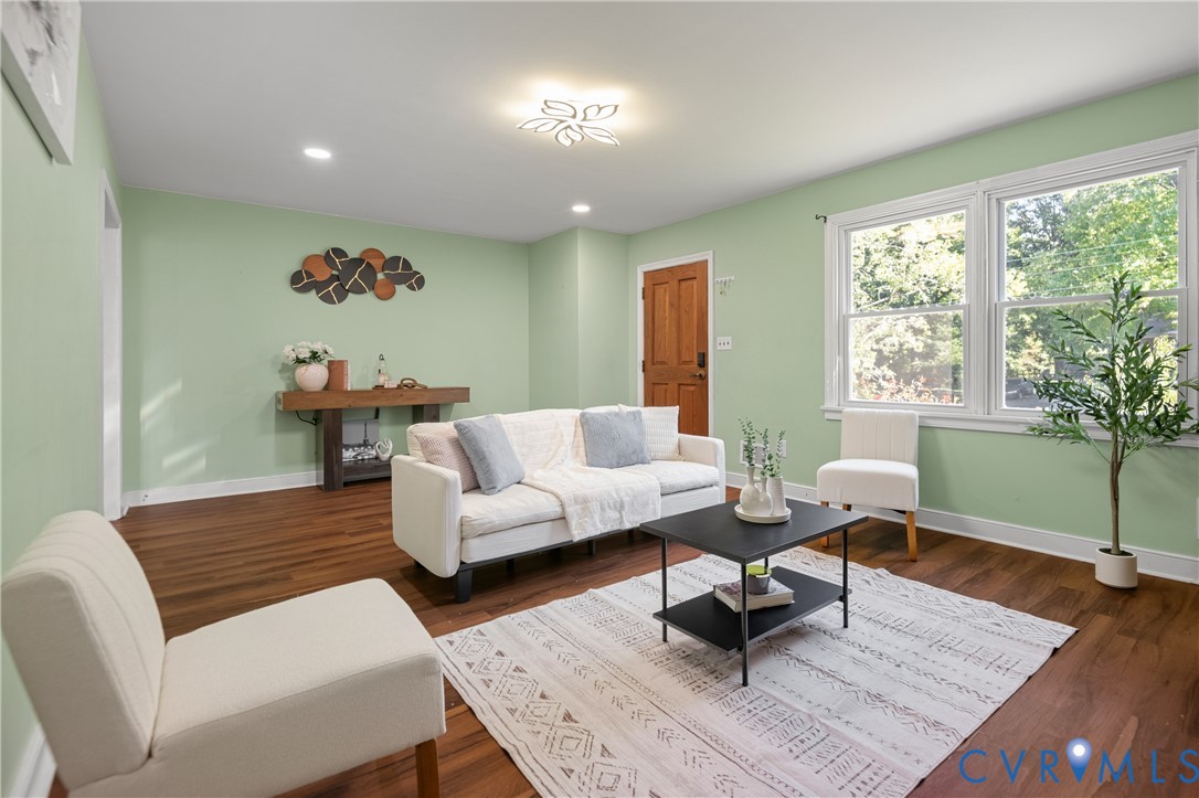 Living space featuring wood-finish flooring, double-hung windows, recessed lighting, and a multi-panel wood door Living space featuring wood-finish flooring, double-hung windows, recessed lighting, and a multi-panel wood door