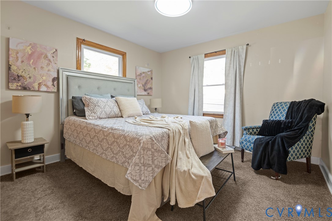 Neutral wall-to-wall carpeting, wood-frame windows, and a flush-mount circular ceiling light fixture