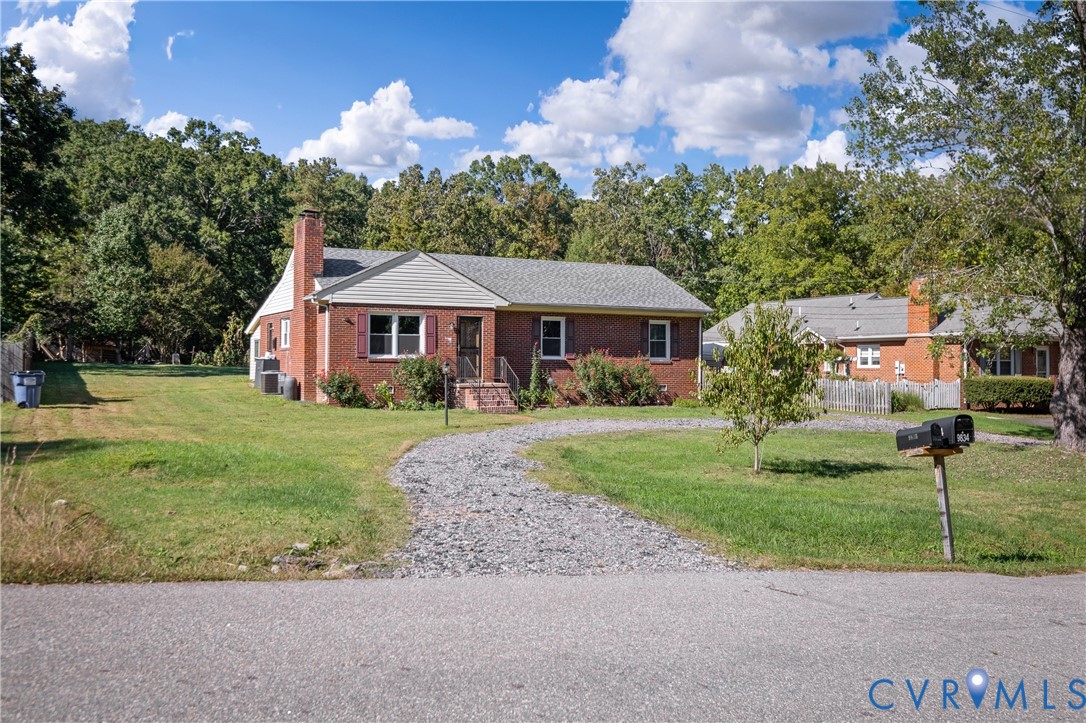 Single-story brick exterior featuring a gable roof, vinyl-sided gables, shuttered windows, and a gravel driveway
