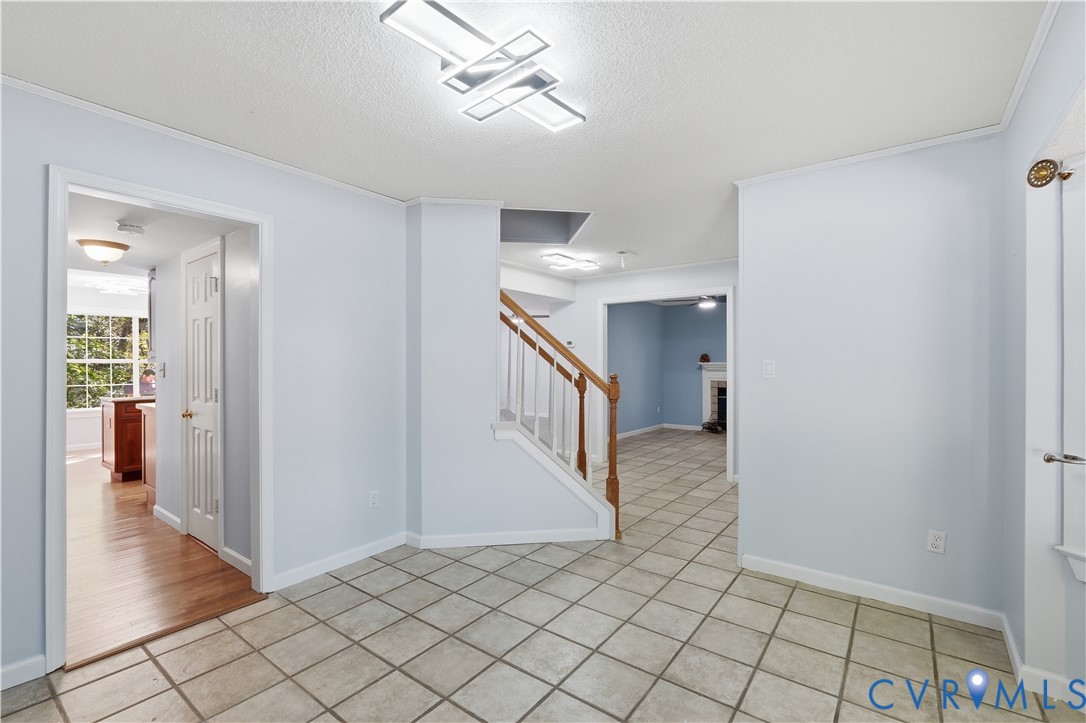 Interior foyer featuring tile flooring, staircase with a wood handrail, and modern geometric flush-mount light fixtures