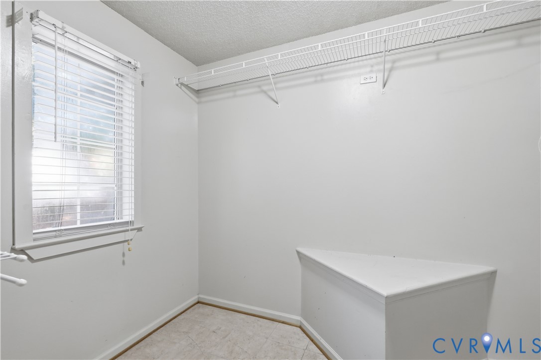 Interior room featuring a window with horizontal blinds, built-in wire shelving, and a triangular built-in platform