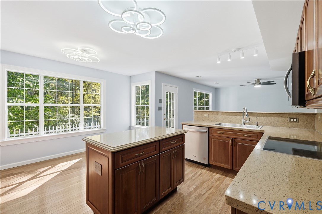 Kitchen featuring wood cabinetry, solid-surface countertops, center island, wood-finish flooring, and modern geometric flush-mount lighting