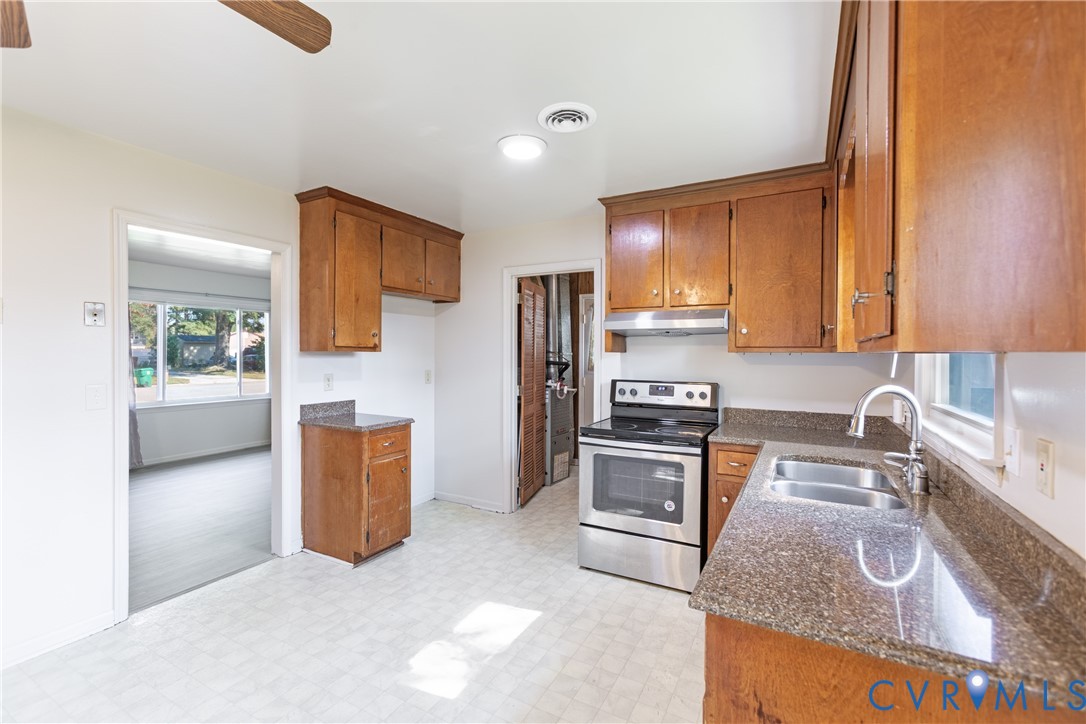 Kitchen featuring wood cabinetry, stone-finish countertops, a stainless steel range, and a dual-basin sink with a goose-neck faucet