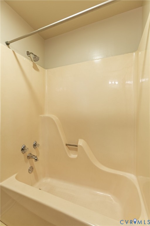 Full-surround acrylic bathtub enclosure with integrated molded soap dish, chrome showerhead, polished metal faucet assembly, and overhead tension curtain rod