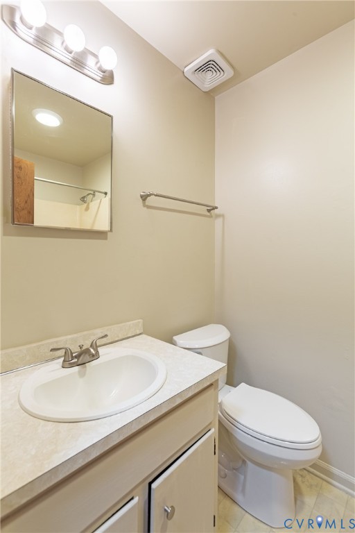 Vanity featuring a stone-patterned countertop, integrated oval basin, brushed-metal hardware, a wall-mounted rectangular mirror, and a three-light vanity fixture