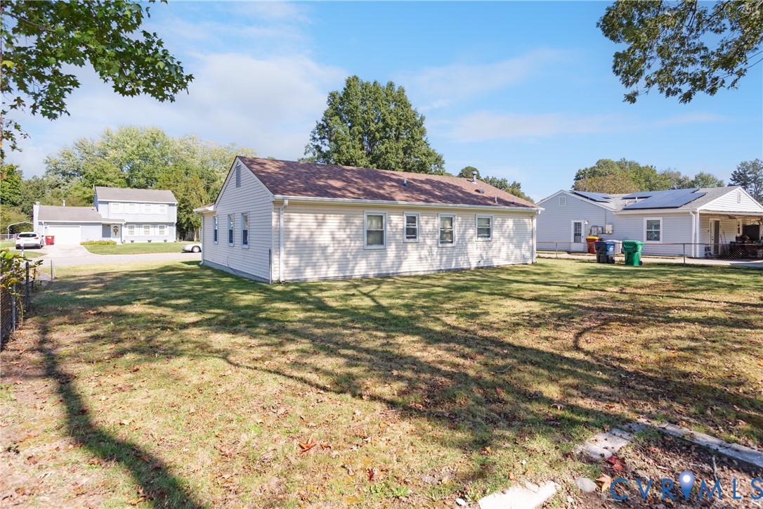 Exterior featuring light-colored horizontal siding, a gabled roofline, and an expansive lawn