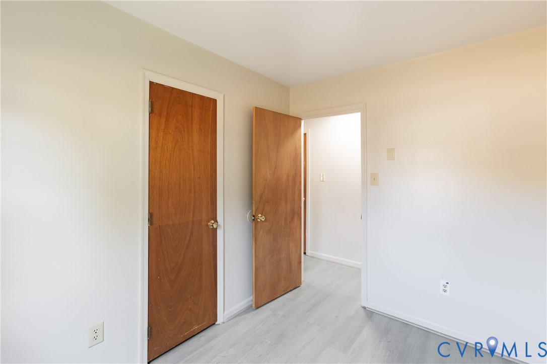 Interior space featuring neutral-toned walls, wood-finish flooring, and solid wood interior doors with metallic hardware