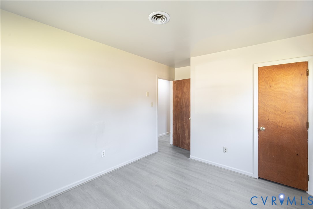 Neutral interior space featuring wood-finish flooring, solid wood-core doors, and smooth-finish walls