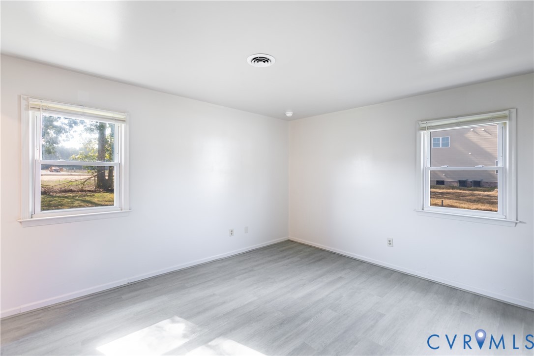 Neutral interior space featuring wood-finish flooring, crisp white wall finishes, and dual double-hung windows