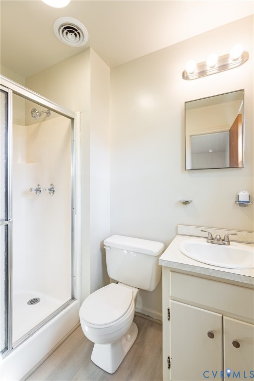 Bathroom featuring a glass-enclosed shower, vanity with an integrated sink, neutral stone-finish countertop, wall-mounted mirror, and three-bulb vanity lighting