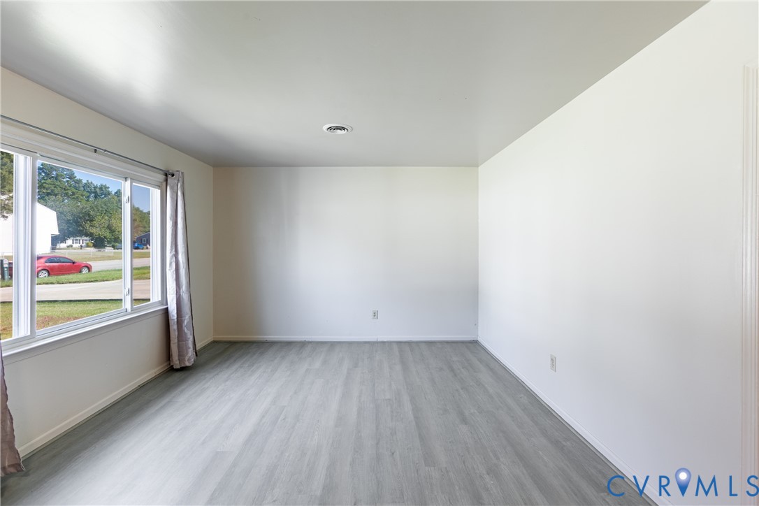Neutral-toned interior space featuring wood-finish flooring, white walls, and a large multi-pane window