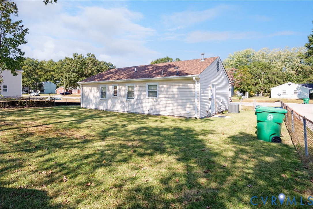 Exterior profile featuring light-toned vinyl siding, an asphalt shingle roof, and a fenced-in grassy yard