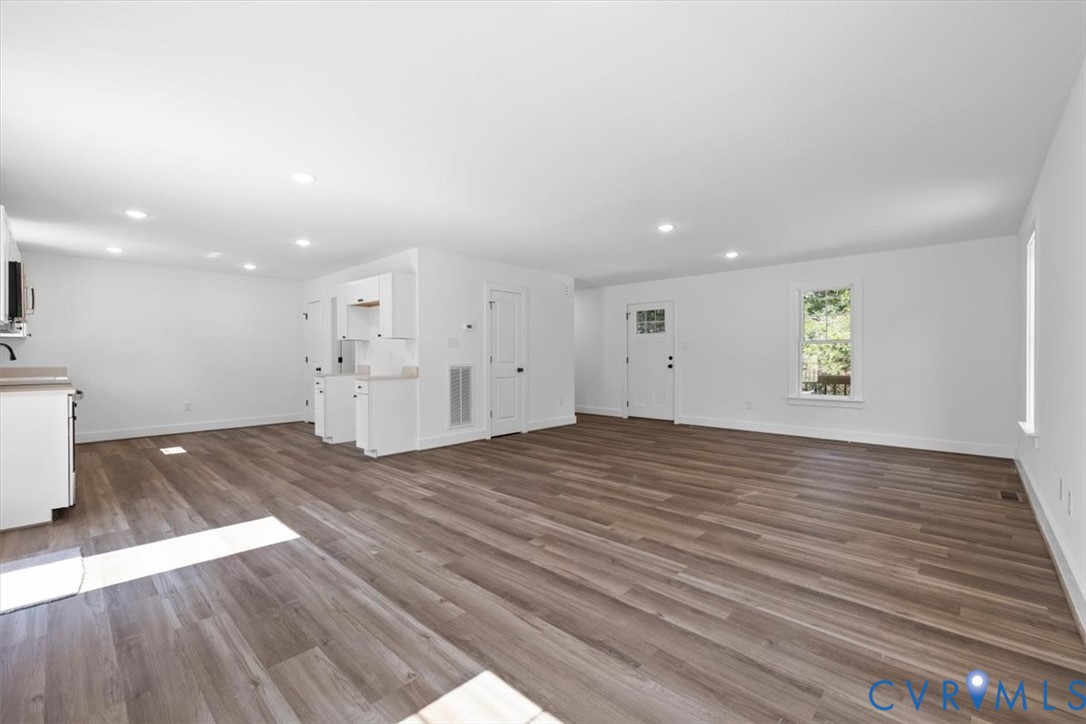 Open floor plan featuring wood-finish flooring, recessed lighting, and white cabinetry