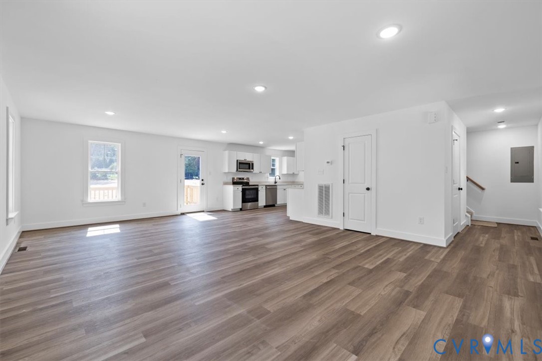 Open-concept interior featuring wood-finish flooring, recessed lighting, and kitchen cabinetry with integrated appliances