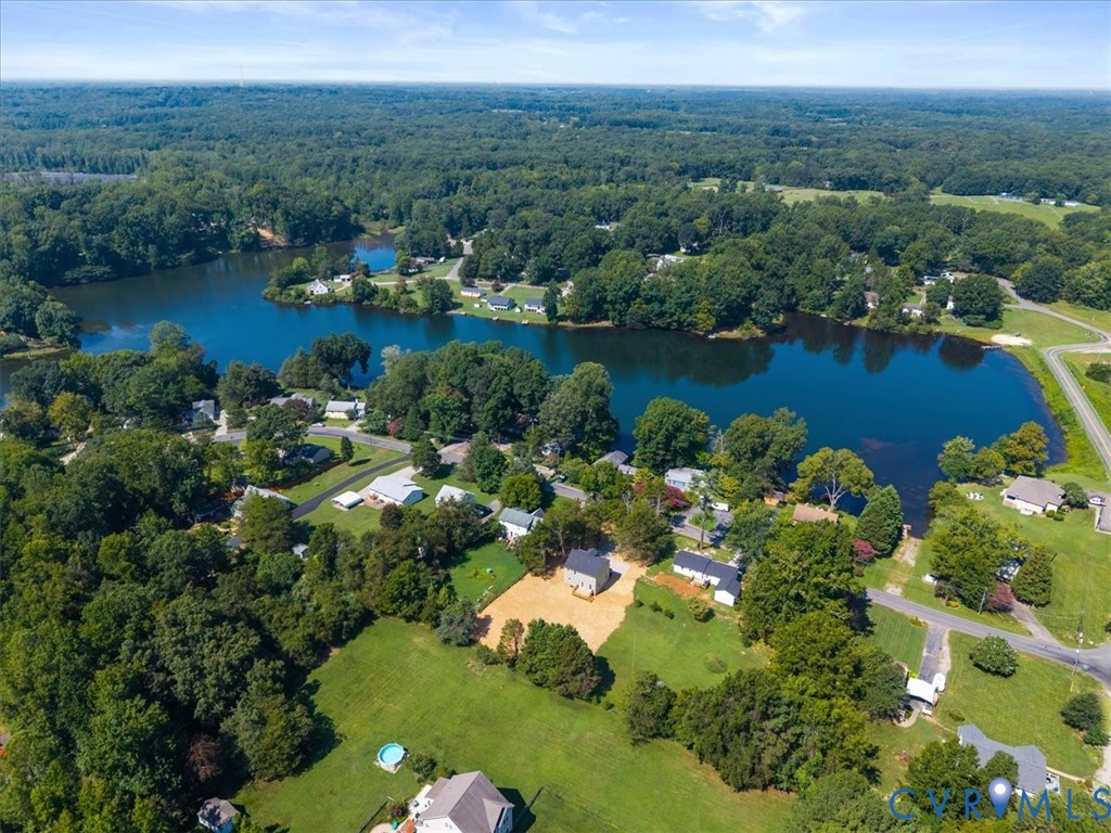 Aerial perspective featuring expansive acreage, mature tree canopy, and direct water frontage