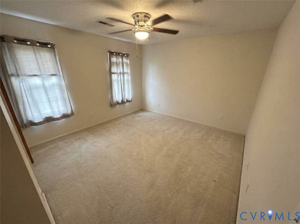Neutral-toned carpeting, dual windows, and a central ceiling fan with integrated lighting