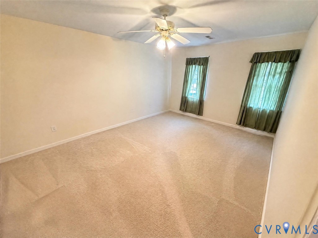 Neutral-toned carpeting, multi-blade ceiling fan with integrated lighting, and dual windows