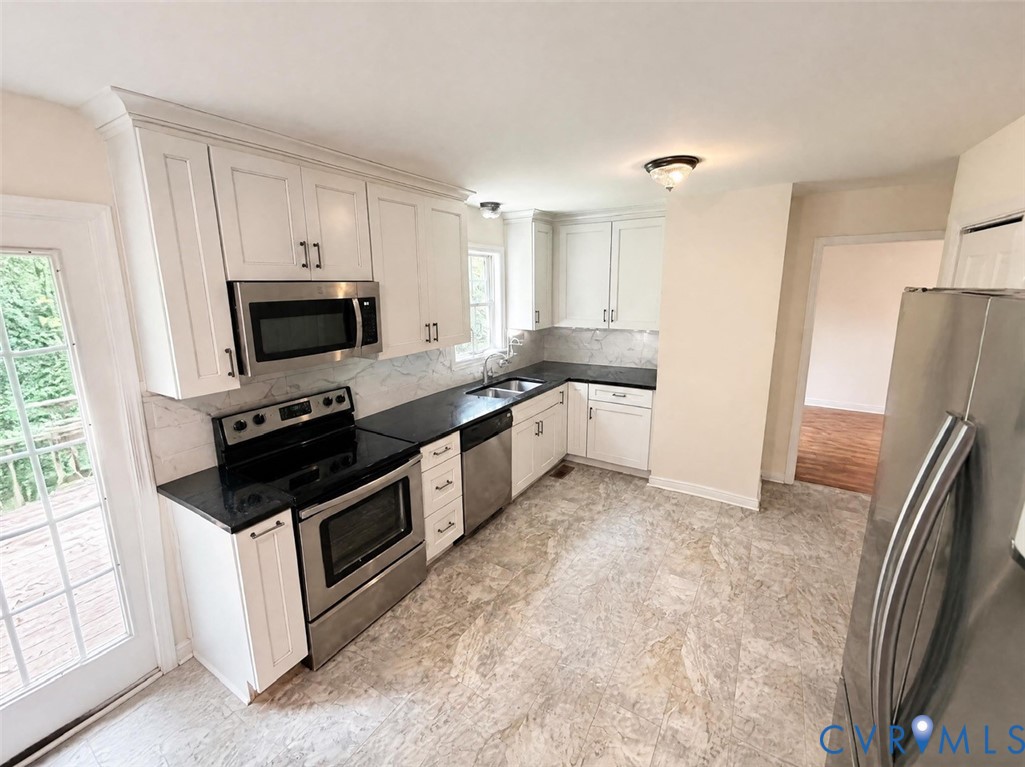 Kitchen featuring white shaker-style cabinetry, dark stone-finish countertops, stainless steel appliances, and tile flooring