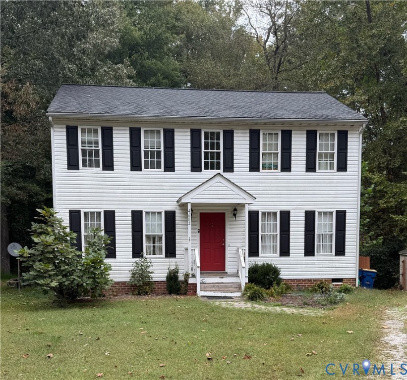 Two-story colonial-style residence featuring white horizontal siding, black shutters, a red entry door, a covered front porch, and a brick foundation trim