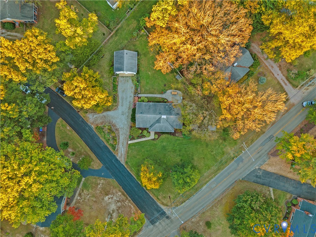 Aerial perspective featuring a lot with mature trees, a detached structure, a paved driveway, and a residential building