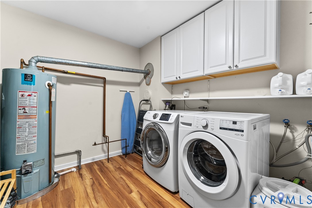 Laundry area featuring wood-finish flooring, white Shaker-style wall-mounted cabinetry, and open shelving