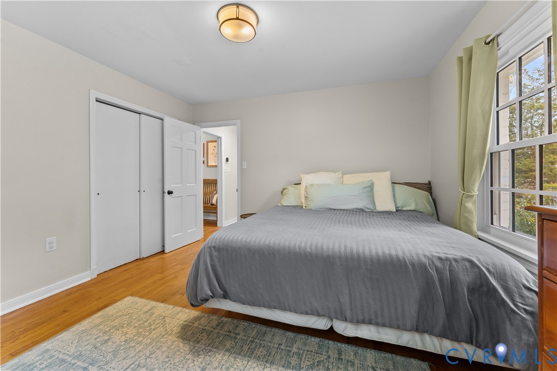 Wood-finish flooring, neutral wall tones, multi-pane window, flush-mount ceiling light, and double-door reach-in closet