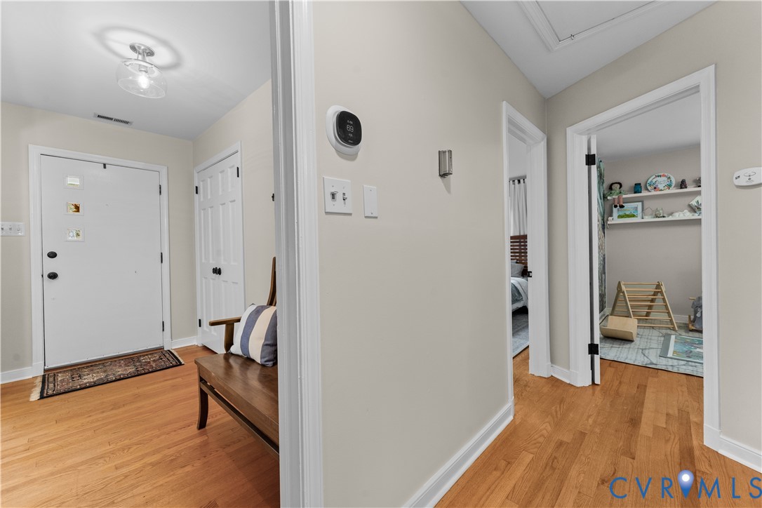 Entryway featuring wood-finish flooring, a flush-mount light fixture, and white interior doors with black hardware