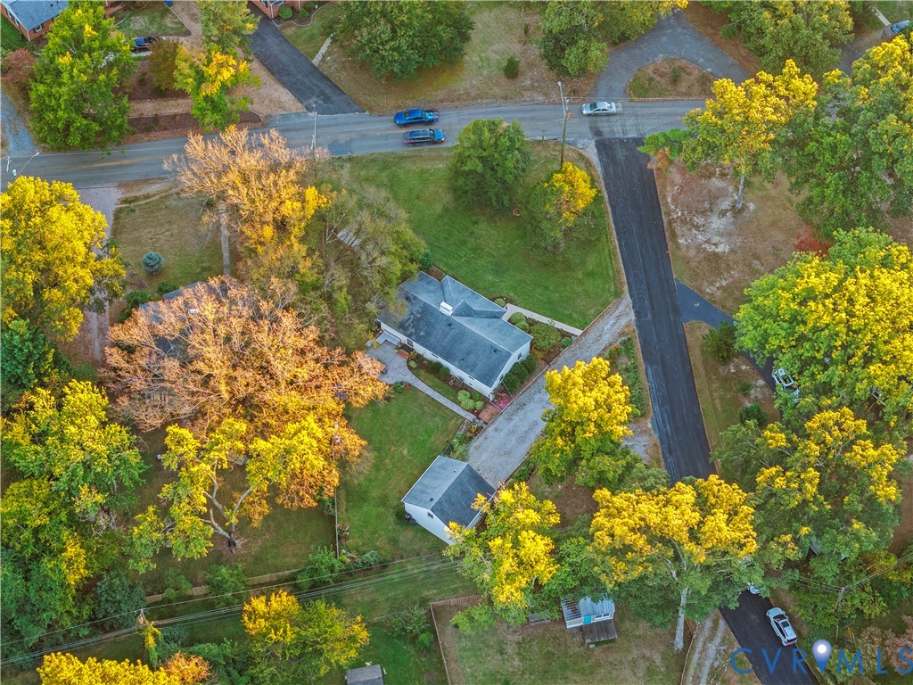 Aerial perspective featuring a lot with mature tree canopy, asphalt driveway, detached structure, and expansive lawn space