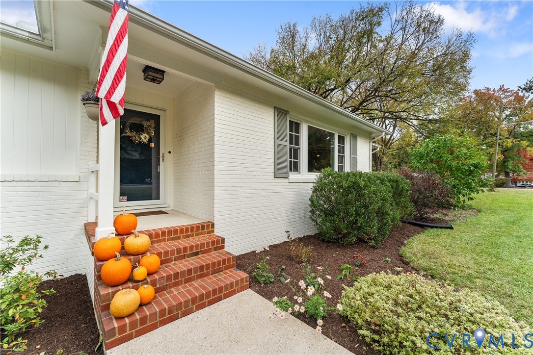 Exterior featuring painted brick siding, multi-tier red brick steps, gray window shutters, and a concrete walkway Exterior featuring painted brick siding, multi-tier red brick steps, gray window shutters, and a concrete walkway