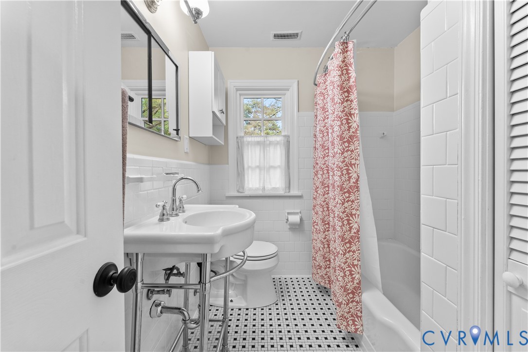 Bathroom featuring a white pedestal sink with chrome plumbing, subway tile wall surround, black-and-white mosaic tile flooring, built-in medicine cabinet, and a multi-pane window