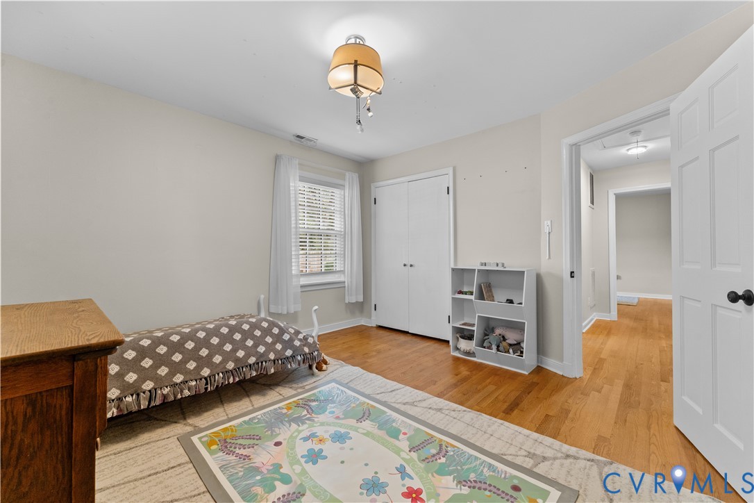 Neutral-toned interior featuring wood-finish flooring, a double-door closet, multi-pane window, and decorative overhead lighting