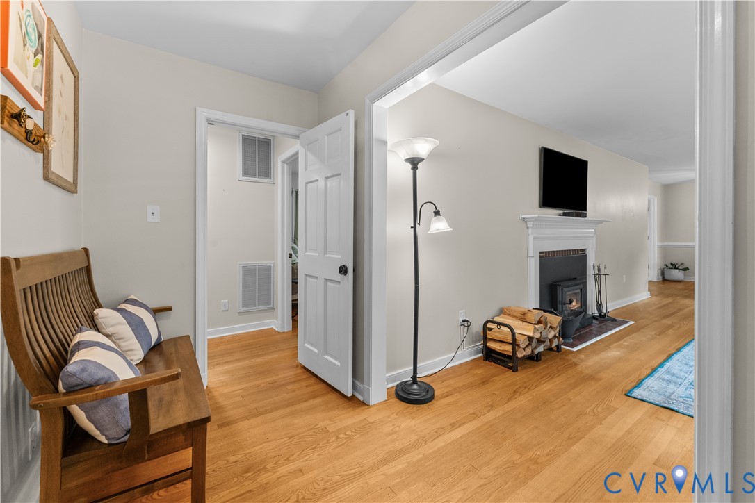 Interior space featuring wood-finish flooring, a traditional fireplace with a white mantel, and a six-panel interior door