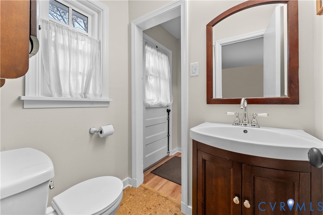 Vanity featuring a wood cabinet and integrated sink with polished metal hardware, crowned by a wooden-framed mirror