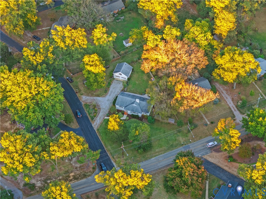 Aerial perspective featuring a residential lot with mature trees, a detached garage, and an asphalt driveway