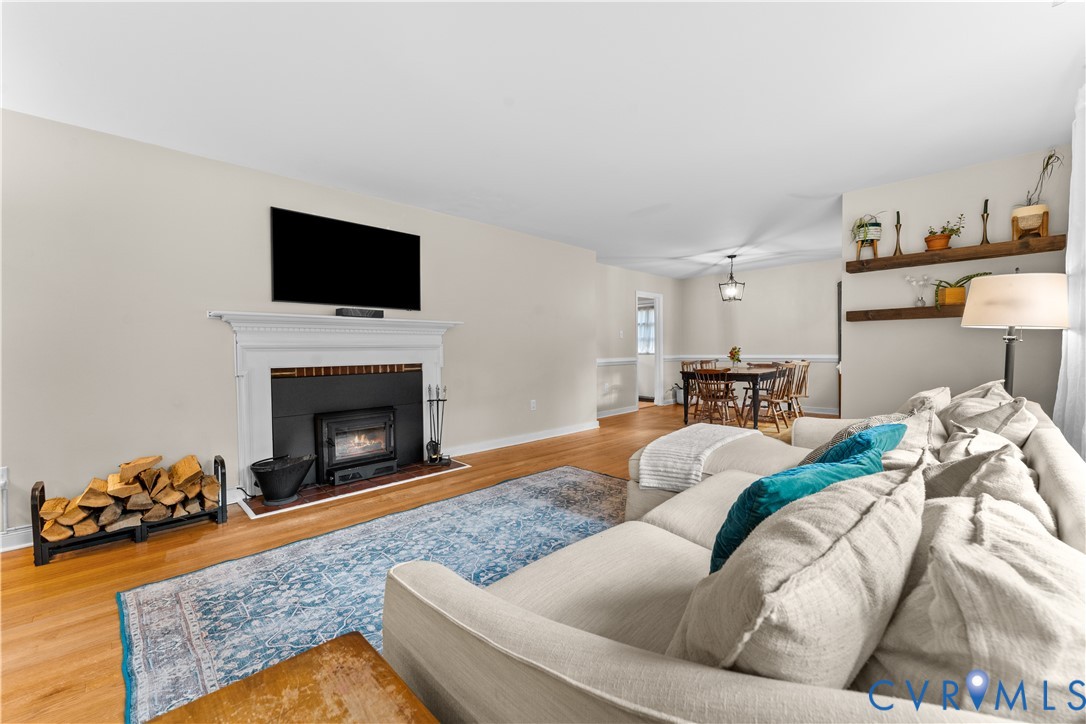Fireplace with a classic white mantel, wood-finish flooring, and natural wood floating wall shelves
