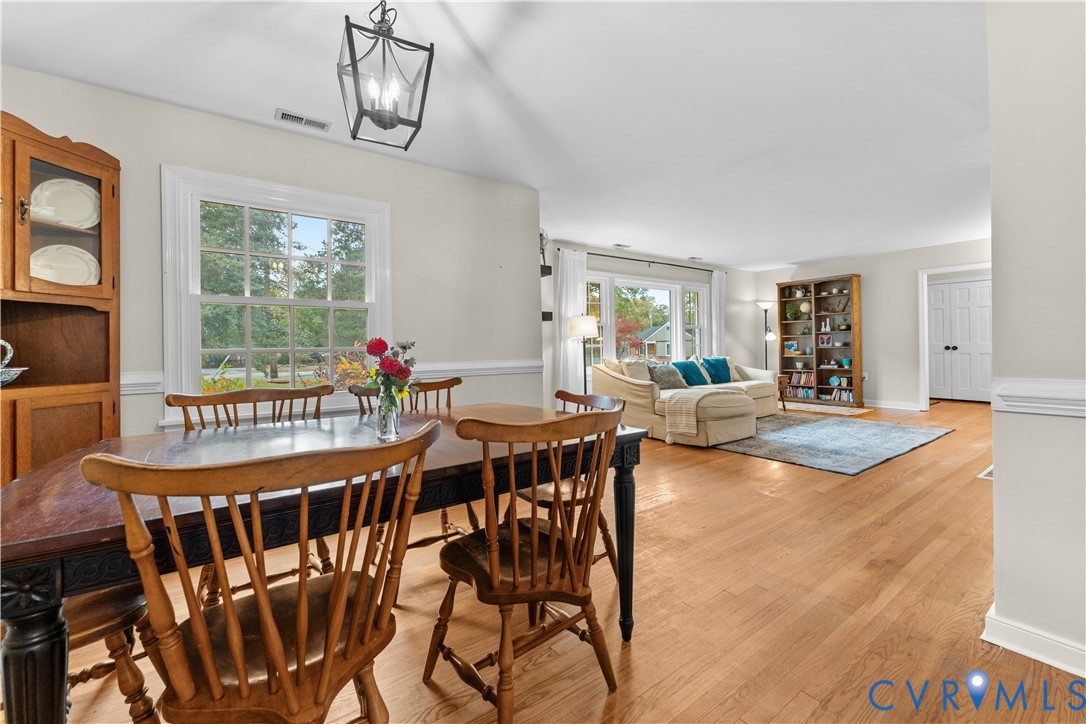 Interior space featuring wood-finish flooring, white chair rail molding, multi-pane windows, and a metal lantern-style hanging light fixture