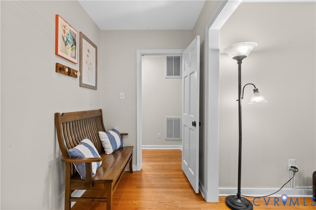 Interior space featuring polished wood-finish flooring, neutral wall paint, and a six-panel interior door