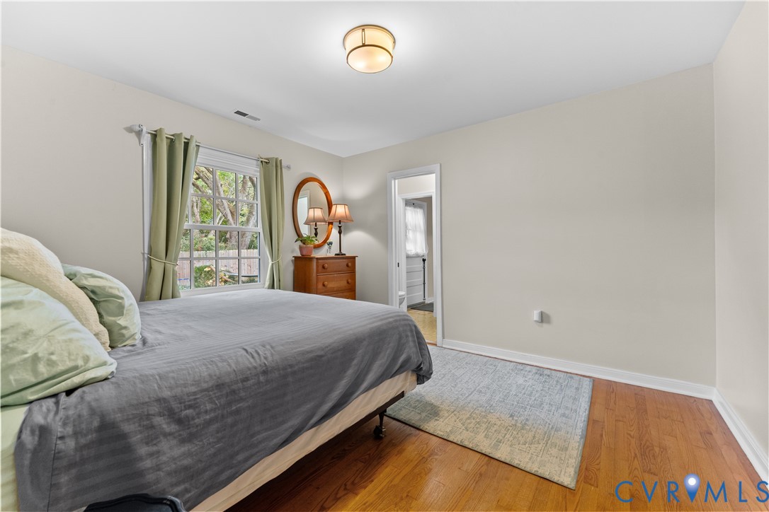 Room featuring wood-finish flooring, a neutral paint palette, a multi-pane window, and a semi-flush mount ceiling light fixture