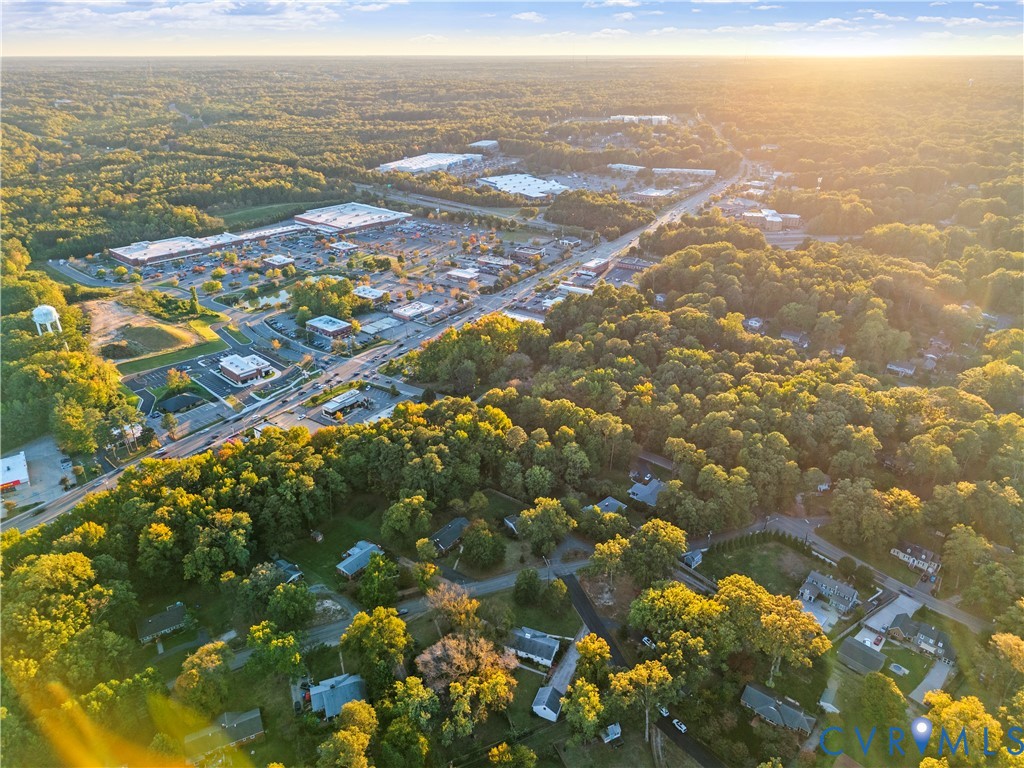 Aerial perspective featuring established tree canopy, surface roadways, and nearby commercial developments