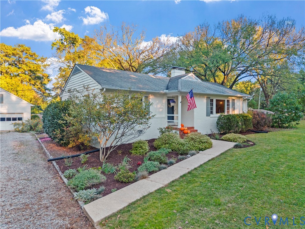 Painted brick exterior featuring a covered entryway, shingled roof, mature landscaping, and a gravel driveway Painted brick exterior featuring a covered entryway, shingled roof, mature landscaping, and a gravel driveway