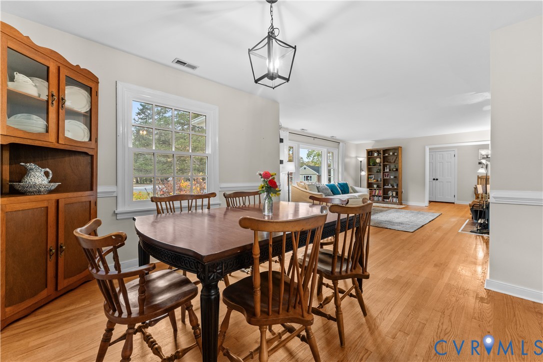 Dining area featuring wood-finish flooring, a geometric-frame lantern pendant light, and wainscoting